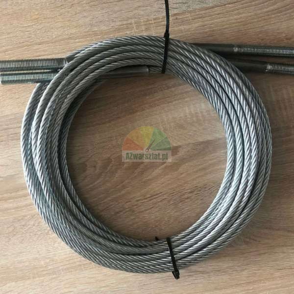 Coiled steel wire rope with threaded ends secured with cable ties on a wooden surface.
