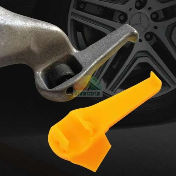 Metal tire changer mount demount head with a yellow plastic protector insert against a car wheel background.