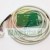 Green PCB circuit board with a soldered white cable and a connector on a white background.
