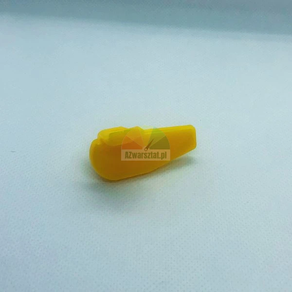 Small yellow plastic component or spare part on a plain light background.
