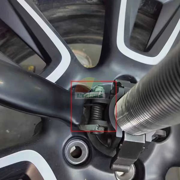 Close-up of a black alloy wheel rim mounted on a balancing machine with a red square highlighting the mounting clamp mechanism.