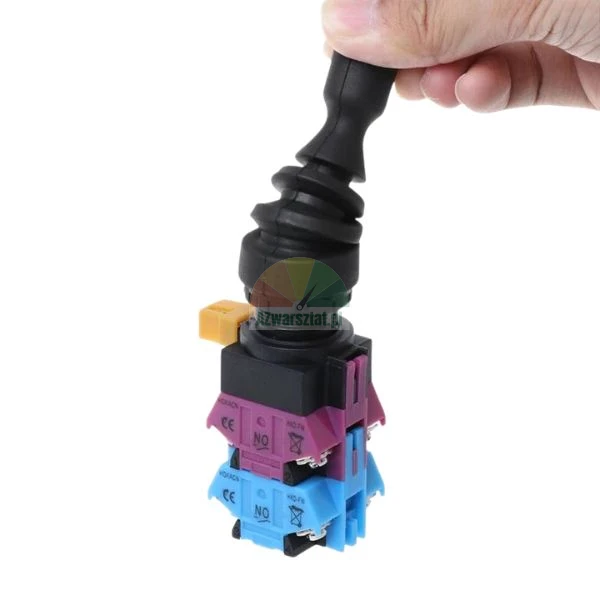 Hand holding an industrial joystick switch with a flexible rubber boot and colored contact blocks